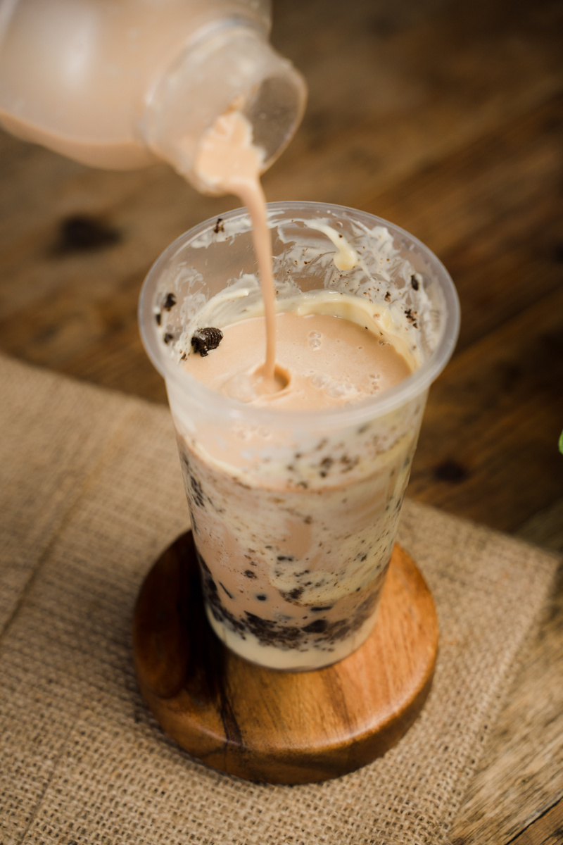 Bottle Pouring Milk Tea in a Glass on Burlap Cloth